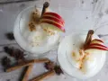 Zwei cremige Wintercocktails mit Zimt, Apfelscheiben und Sternanis.