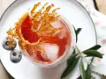 Ein erfrischender Sling Cocktail mit Blutorange, gefrorenen Beeren und Karamell-Dekoration.