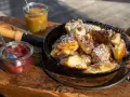Ein frisch zubereiteter Kaiserschmarrn im Pfännchen, bestäubt mit Puderzucker, daneben Apfelmus und Zwetschgenröster. Ein leckeres Kaiserschmarrn Rezept zum Nachmachen.