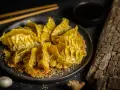 Goldbraune Gyoza auf knusprigem Sesam-Bett, bereit für ein köstliches Dumplings-Rezept. Dazu Sojasauce und Ingwer.