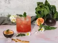 Erfrischender sanbitter cocktail mit Passionsfrucht, Minze und Eiswürfeln, garniert mit Gänseblümchen.