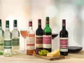 Eine Auswahl an Bio-Weinen, darunter verschiedene Weißwein Sorten wie Riesling und Chardonnay, neben Rot- und Roséweinen, Käse und Trauben.