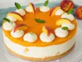 Eine Maracuja Torte mit Pfirsichstücken und Sahnetupfern, verziert mit Minze.