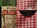 Ein Glas Rotwein neben einer Flasche Château La Grace Dieu. Die Bedeutung von "Grand Cru" auf dem Etikett deutet auf höchste Qualität hin.
