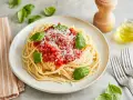 Ein Teller Spaghetti Napoli mit Tomatensauce, Parmesan und frischem Basilikum.