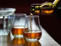 Bernsteinfarbener schottischer Whisky fließt aus einer Flasche in ein Glas. Die schottischer Whisky sorten alphabetisch zu verkosten ist ein Genuss.