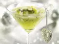 Erfrischender Kiwi-Cocktail im Martiniglas, garniert mit frischen Kiwischeiben und einem glitzernden Herz-Anhänger.