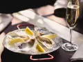 Frische Austern auf Eis mit Zitronenspalten und einem Glas prickelnden Weins – ein Genuss für alle Sinne.