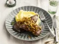 Leber braten mit karamellisierten Zwiebeln und Kartoffelpüree auf einem grauen Teller. Ein Klassiker, der immer schmeckt.