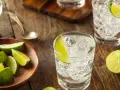 Erfrischender Jean Tonic mit Eis und Limettenspalten auf rustikalem Holztisch.