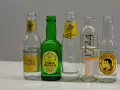 Fünf Flaschen Tonic Water: Fever-Tree, Fentimans, Schweppes, 1724 und Thomas Henry. Sie zeigen, nach was Tonic Water schmeckt: herb-bitter, erfrischend, mit Zitrus- und Kräuternoten.