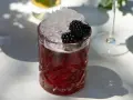 Ein Glas mit einem tiefroten Drink, gefüllt mit zerstoßenem Eis und garniert mit Brombeeren. Perfekt für die besten Cocktails an einem sonnigen Tag.