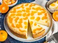 Ein saftiger faule weiber kuchen mit Mandarinenstücken, der auf einem Teller liegt. Daneben liegen frische Mandarinen und eine Tortenschaufel.