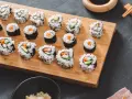 Selbstgemachtes Sushi mit Karotten und Gurken auf einem Holzbrett. So einfach kann Sushi selber machen sein!