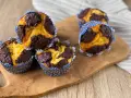 Zupfkuchen Muffins mit Marmormuster aus dunklem Schoko- und hellem Teig in blauen Papierförmchen auf einem Holzbrett.