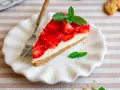 Ein Stück einfache Torte mit Erdbeeren und Minze auf einem weißen Teller.