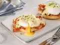 Zwei köstliche Eggs Benedict auf einem Teller, mit flüssigem Eigelb und garniert mit Schnittlauch.