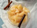 Ein Glas mit süßem Birnenkompott, verfeinert mit Zimtstangen. Perfekt für ein einfaches Birnenkompott Rezept.