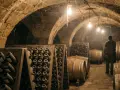 Weinlager mit Flaschenständern und Fässern. Ein Mann steht im Gang, wo die Methode Champenoise zur Reifung des Weins angewendet wird.