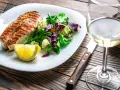 Gegrilltes Lachsfilet mit Salat und Zitrone, dazu ein Glas Weißwein, der den Riesling Geschmack unterstreicht.