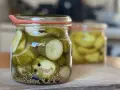 Einmachgläser mit Gurkenscheiben, Zwiebeln und Gewürzen. So werden Gurken eingelegt nach Omas Rezept.