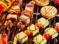 Bunte Spieße mit Tofu, Zucchini, Tomaten und Mais werden auf einem Grill zubereitet. Ein Genuss für vegetarisches Grillen!