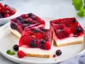 Drei Stücke einer erfrischenden sommertorte mit Beeren und Gelee auf einem Teller.