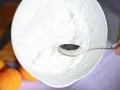 Eine Schüssel mit frisch geschlagener Sahne, bereit für ein Dessert. Ein Löffel ruht in der luftigen Masse.