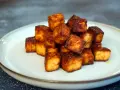 Goldbraun gebratene Tofuwürfel, perfekt zum tofu zubereiten. Knusprig und lecker auf einem Teller angerichtet.