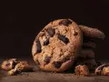 Ein Stapel saftiger american cookies mit Schokoladenstückchen auf einem Holztisch.