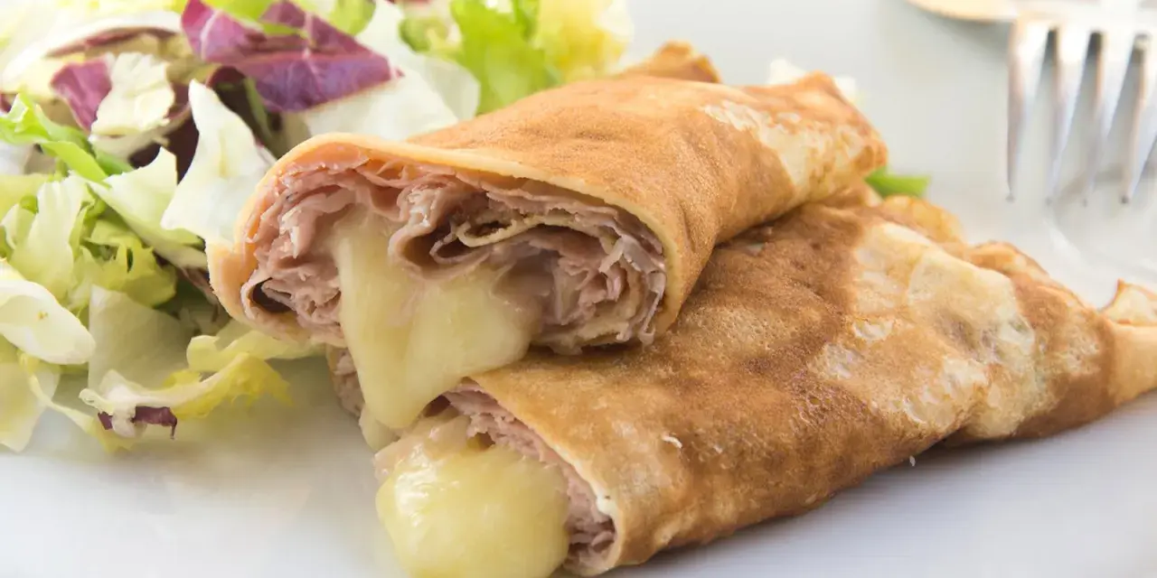 Herzhafte Pfannkuchen gefüllt mit Schinken und geschmolzenem Käse, serviert mit einem frischen Salat.
