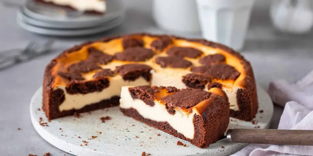 Ein saftiger russischer Zupfkuchen mit cremigem Käsekuchen und schokoladigen Streuseln. Ein Stück wurde bereits herausgeschnitten.