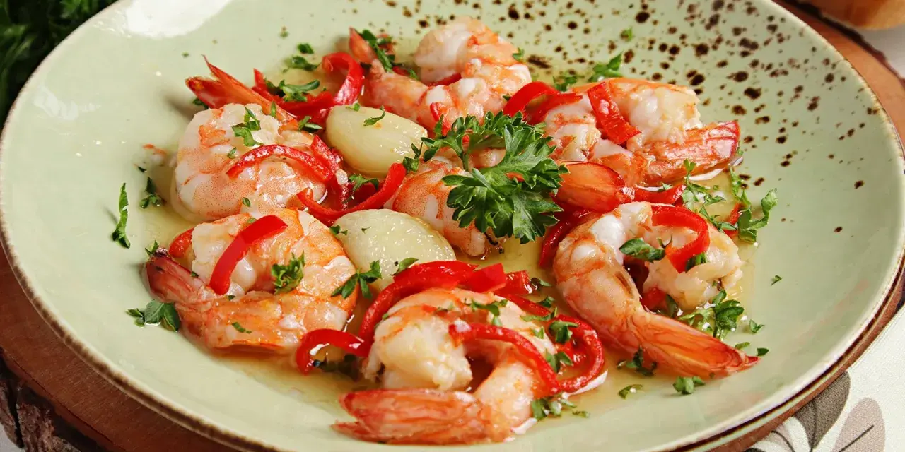 Garnelen in Knoblauchöl mit Paprika und Petersilie, ein köstliches Gericht, das perfekt zu einem Glas Wein passt.
