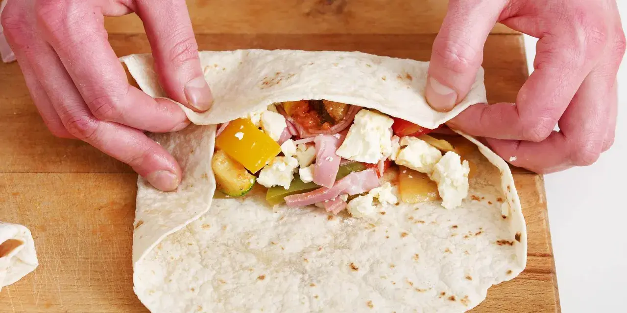 Hände falten wraps mit Gemüse, Schinken und Käse.