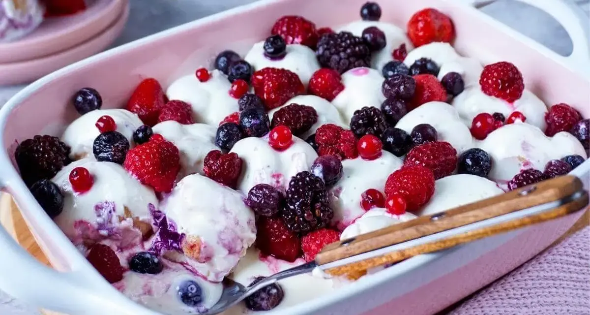 Cremiger Windbeutel-Dessert-Auflauf mit frischen Beeren wie Himbeeren, Blaubeeren und Brombeeren.