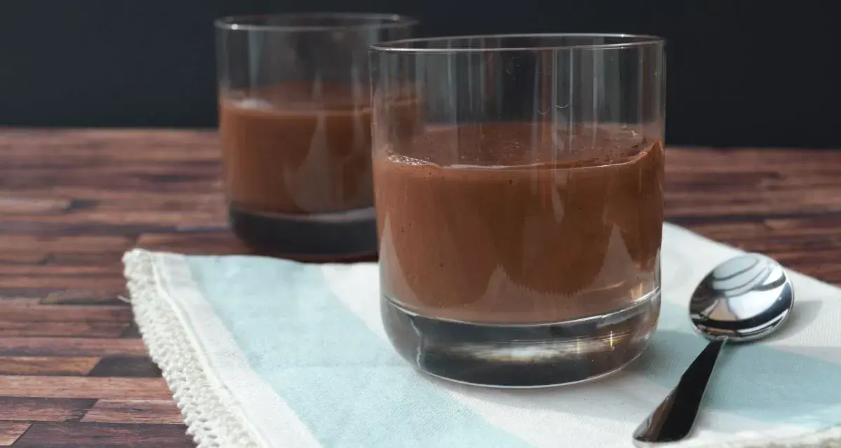 Zwei Gläser cremiger Schokopudding, perfekt zum Schokopudding selber machen. Ein Löffel liegt bereit.