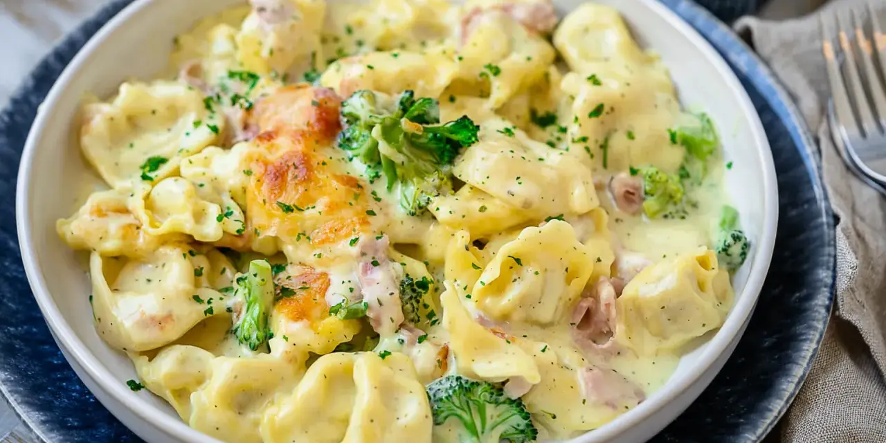 Ein cremiger Tortellini Auflauf mit Brokkoli und Schinken, überbacken mit Käse und bestreut mit Petersilie.