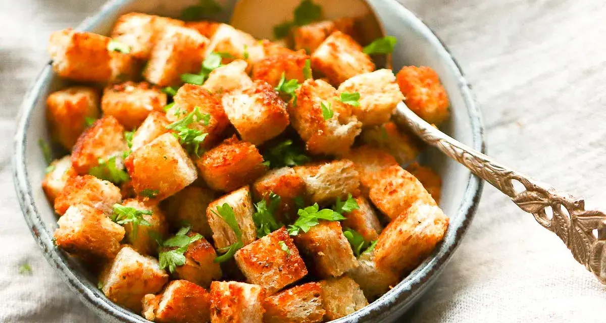 Goldbraune, knusprige Croutons, frisch zubereitet, garniert mit Petersilie in einer Schüssel. Perfekt zum **Croutons selber machen** für Salate oder Suppen.