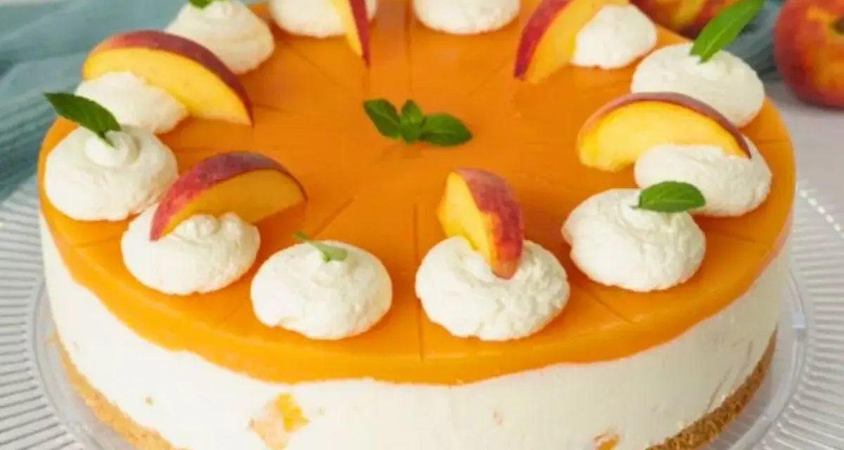 Eine Maracuja Torte mit Pfirsichstücken und Sahnetupfern, verziert mit Minze.