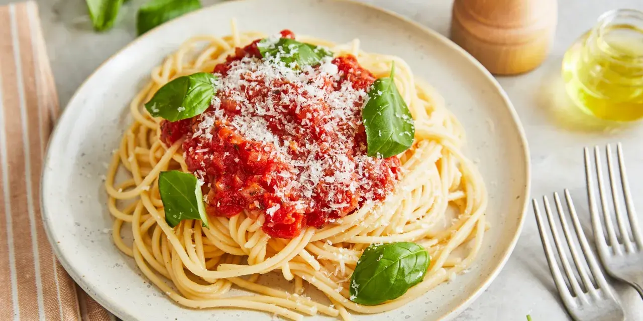 Ein Teller Spaghetti Napoli mit Tomatensauce, Parmesan und frischem Basilikum.