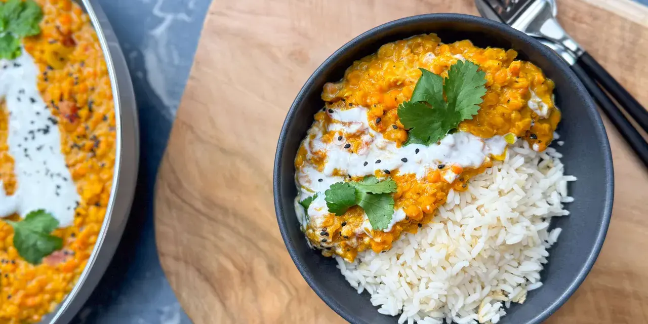 Herzhafte Linsen Rezepte: Cremiges Dal mit Reis, garniert mit Koriander und Kokosmilch. Ein köstliches Gericht, das Wärme und Geschmack vereint.
