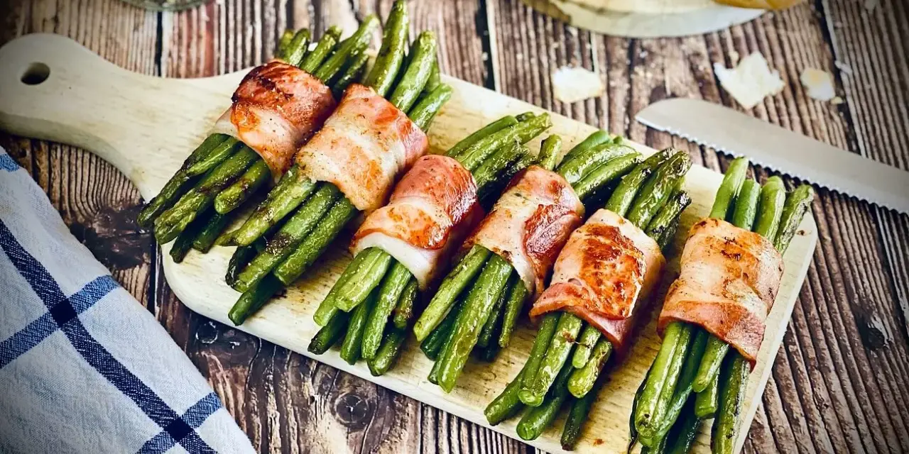 Leckeres Speckbohnen Rezept: Grüne Bohnen umwickelt mit knusprigem Speck, serviert auf einem Holzbrett.
