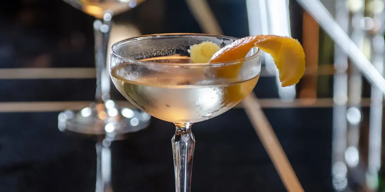 Ein klassischer James Bond Vesper Martini, garniert mit einer Zitronenzeste, in einem eleganten Glas.