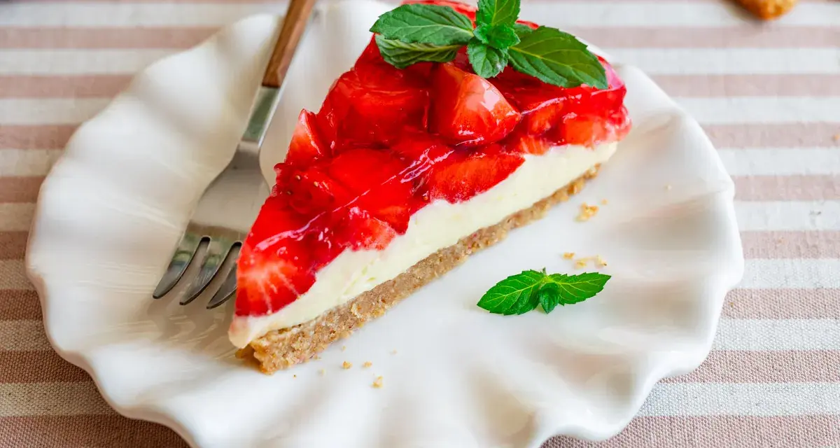Ein Stück einfache Torte mit Erdbeeren und Minze auf einem weißen Teller.
