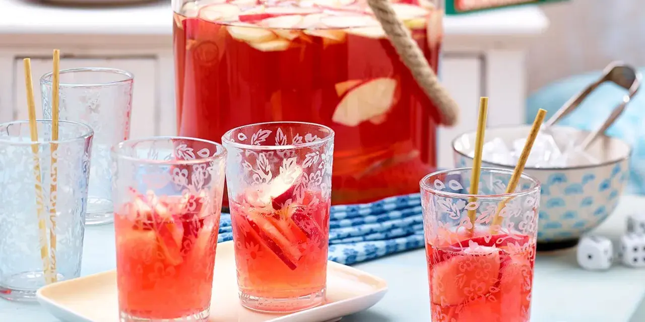 Erfrischende alkoholfreie Bowle mit Apfelstücken in Gläsern, bereit für ein sommerliches Treffen.