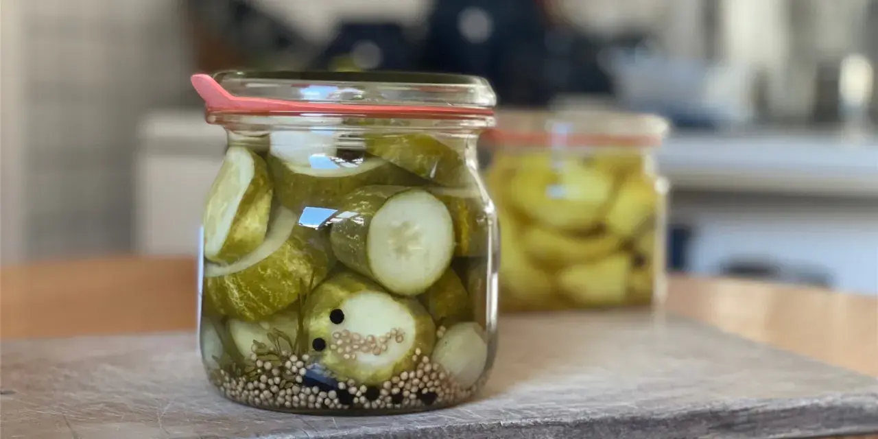 Einmachgläser mit Gurkenscheiben, Zwiebeln und Gewürzen. So werden Gurken eingelegt nach Omas Rezept.