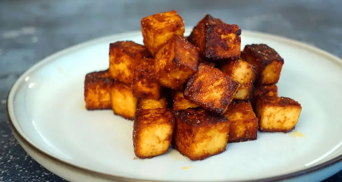 Goldbraun gebratene Tofuwürfel, perfekt zum tofu zubereiten. Knusprig und lecker auf einem Teller angerichtet.