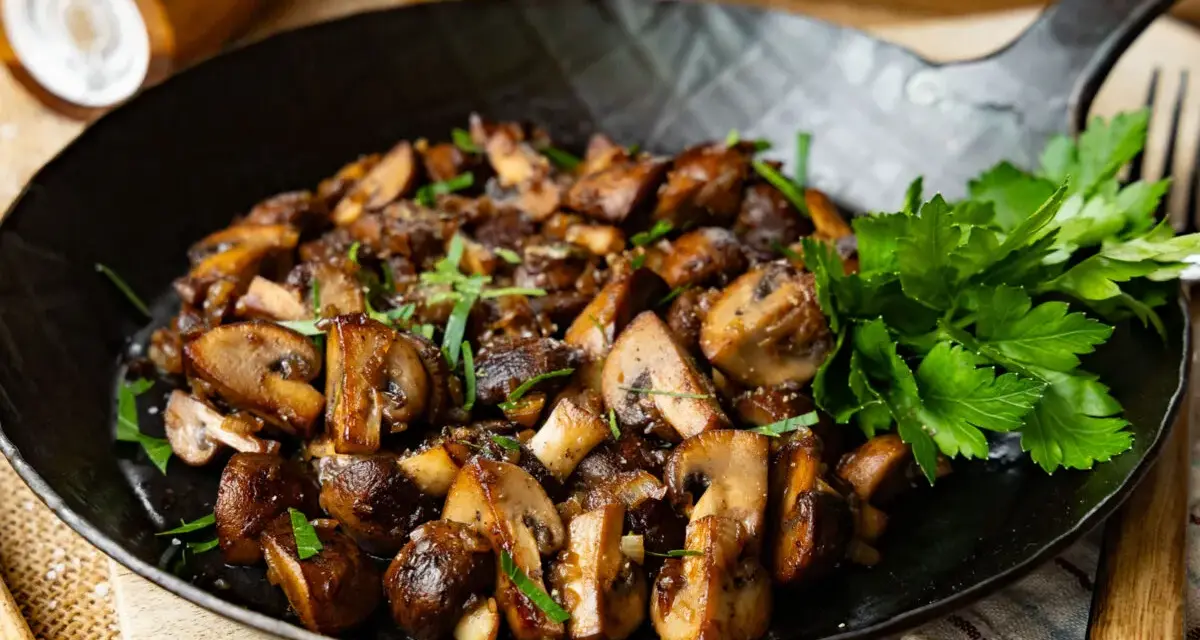 Gebratene Champignons in einer Pfanne, garniert mit frischer Petersilie. Köstlich und einfach zuzubereiten.