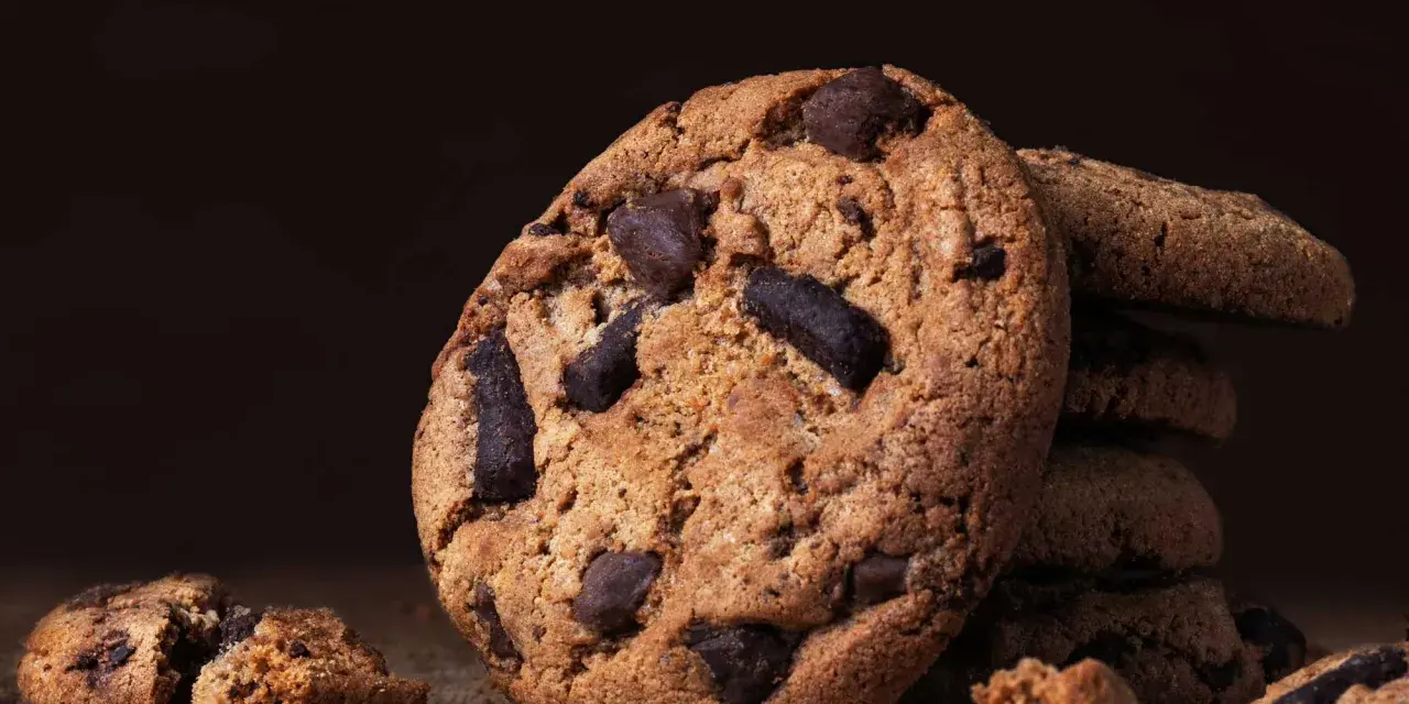 Ein Stapel saftiger american cookies mit Schokoladenstückchen auf einem Holztisch.