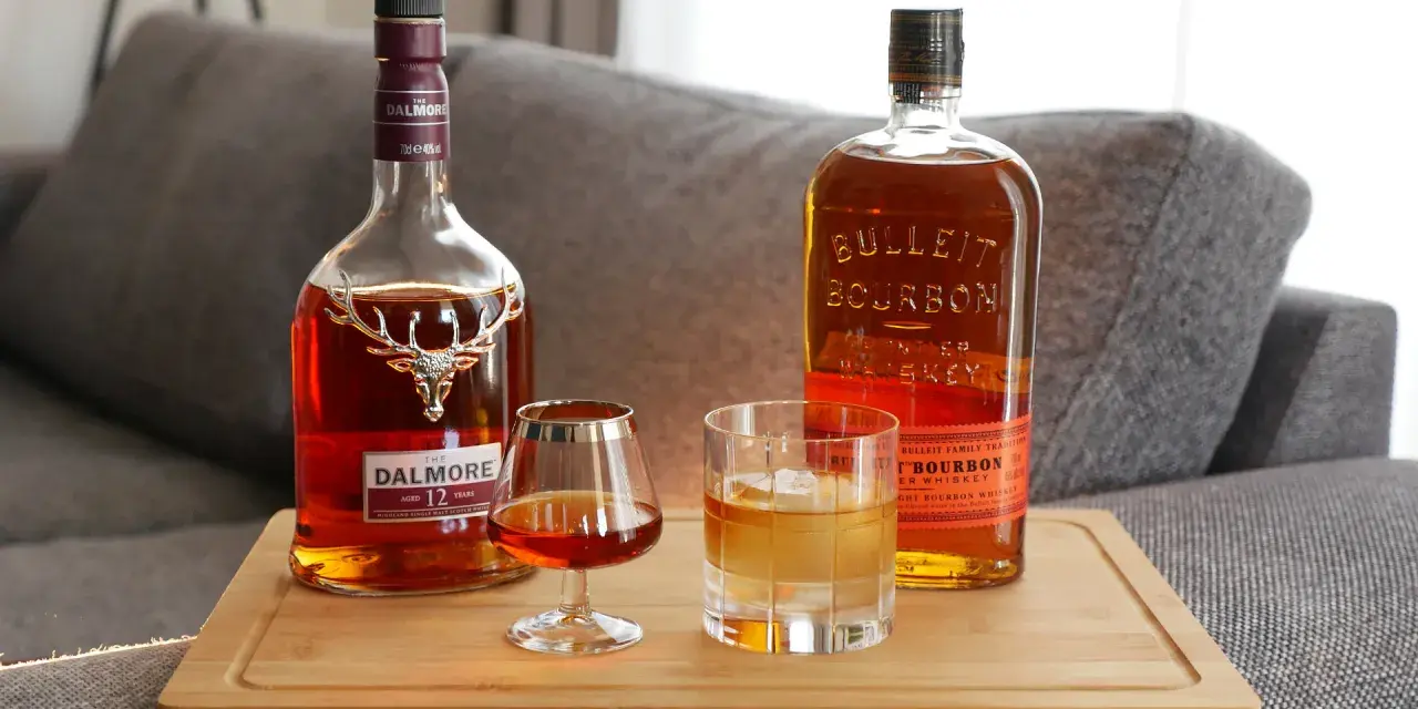 Zwei Flaschen und Gläser mit Whiskey zeigen die whiskey sorten unterschiede: ein Dalmore Scotch und ein Bulleit Bourbon.